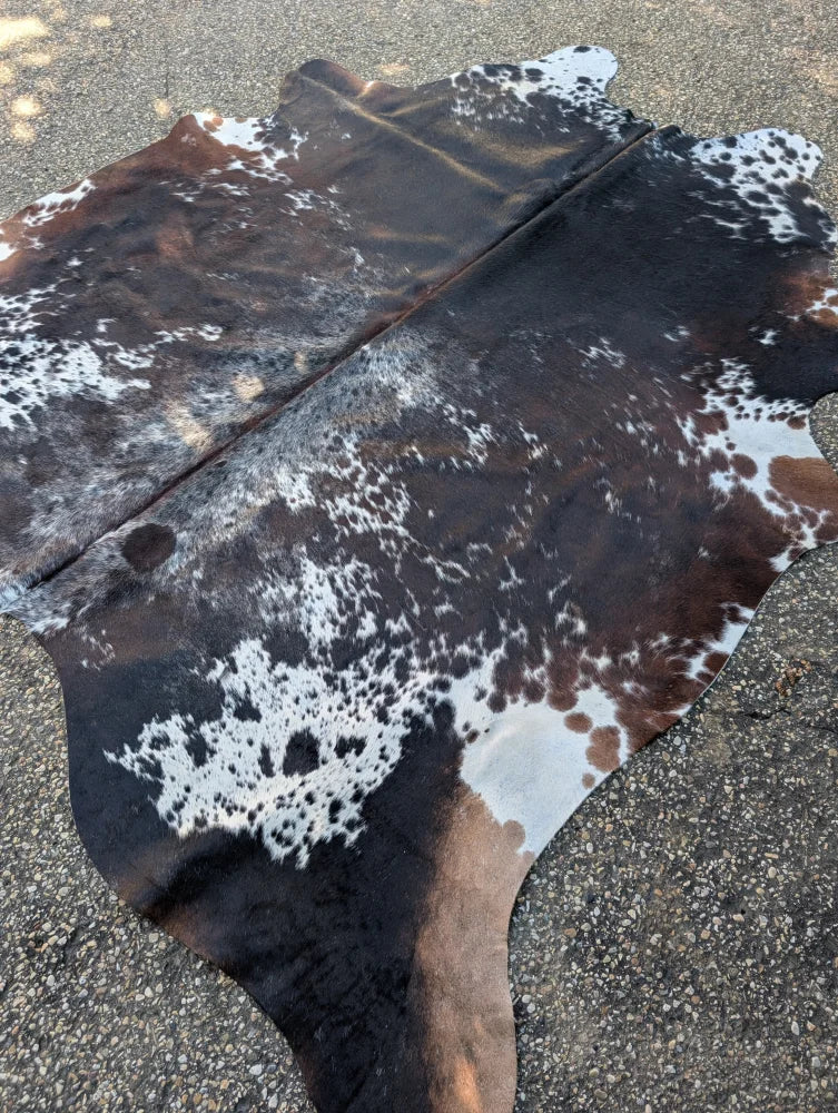 Brown and white spotted large cowhide rug with natural leather texture featuring unique characteristics and rustic charm