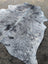 Large speckled gray and black cowhide rug with natural edges showcasing unique characteristics and rustic charm