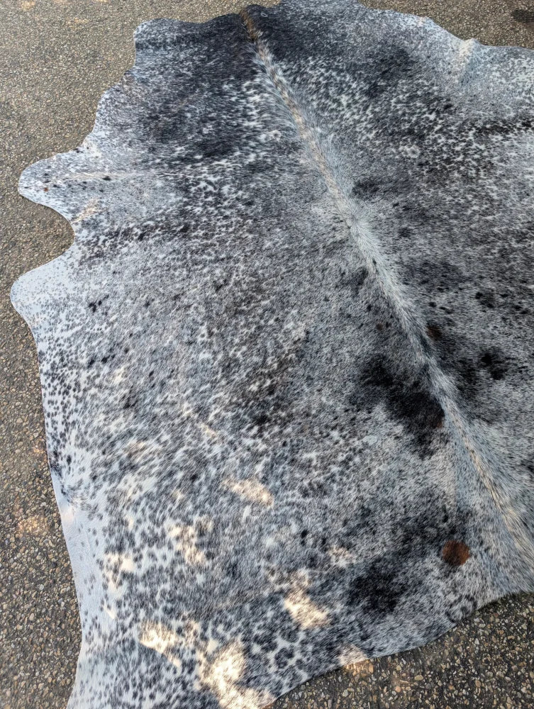 Large gray and black speckled cowhide rug with unique characteristics and rustic charm in a massive 102 by 87 size