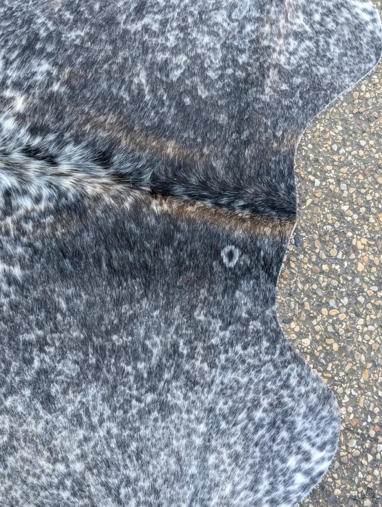 A large saltpeptricolour black and white speckled cowhide rug with unique characteristics and rustic charm