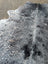 Gray and black speckled large cowhide rug with natural fur texture showcasing unique characteristics and rustic charm