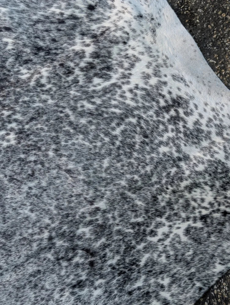 A large cowhide rug with soft white and black speckled faux fur showcasing unique characteristics and rustic charm
