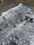 A large gray and black speckled cowhide rug with unique characteristics and rustic charm in a natural irregular edge