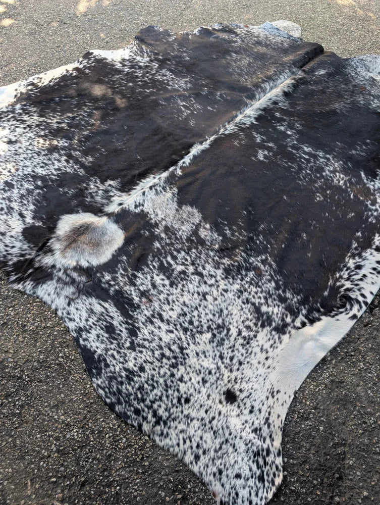 Large saltpeptricolour cowhide rug with black and white spots showcasing unique characteristics and rustic charm