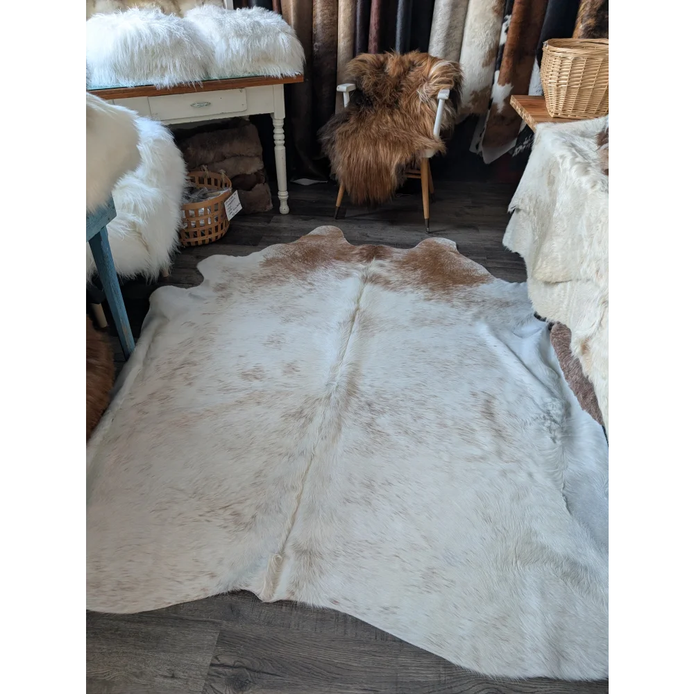 A large angus oliver cowhide rug in soft natural white and brown with a fluffy textured surface perfect for beautiful rugs