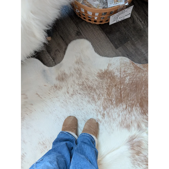 Tan suede boots with white fleece lining worn over blue jeans on a beautiful rugs large cowhide rug by angus oliver