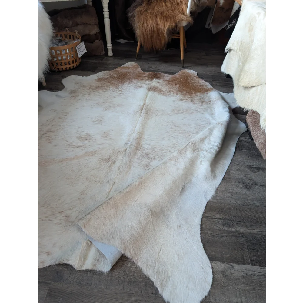 A large cowhide rug by angus oliver in natural white and tan with a soft fluffy texture perfect as beautiful rugs