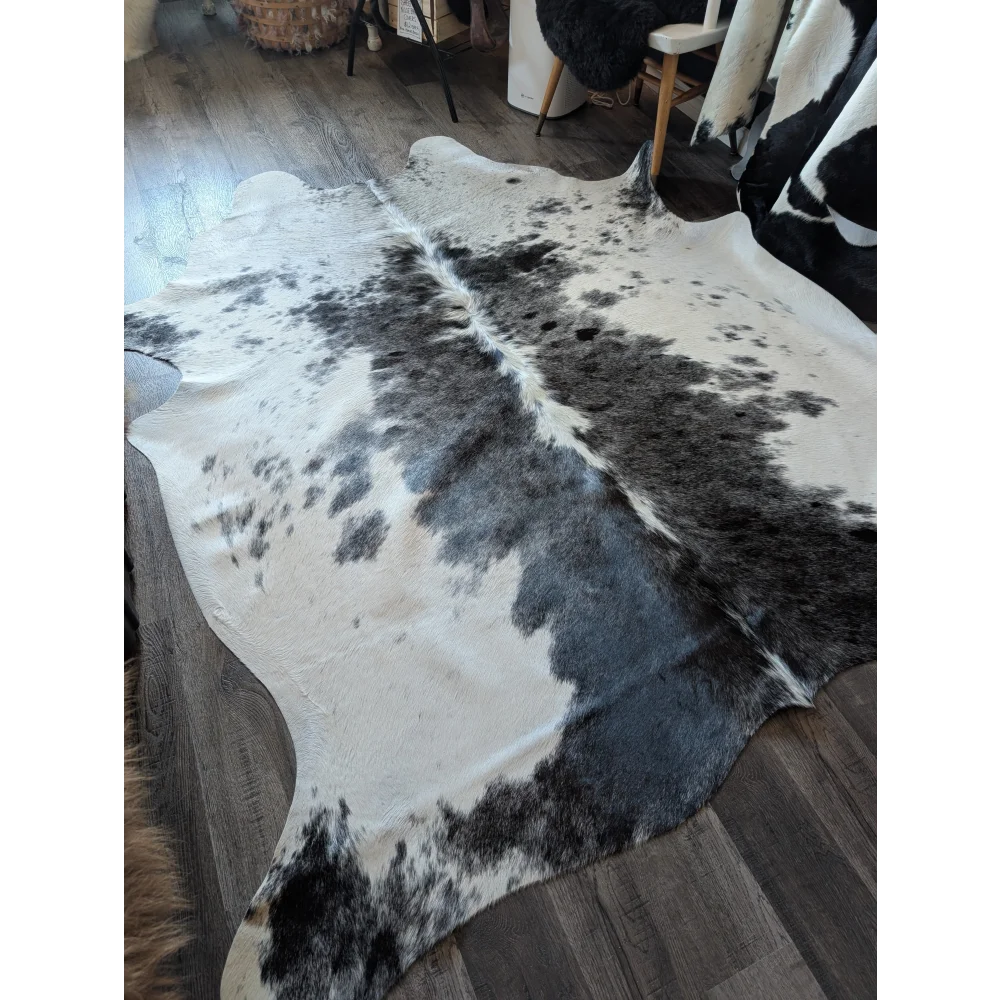 A large black and white natural cowhide rug with a soft textured surface adding rustic charm to any space
