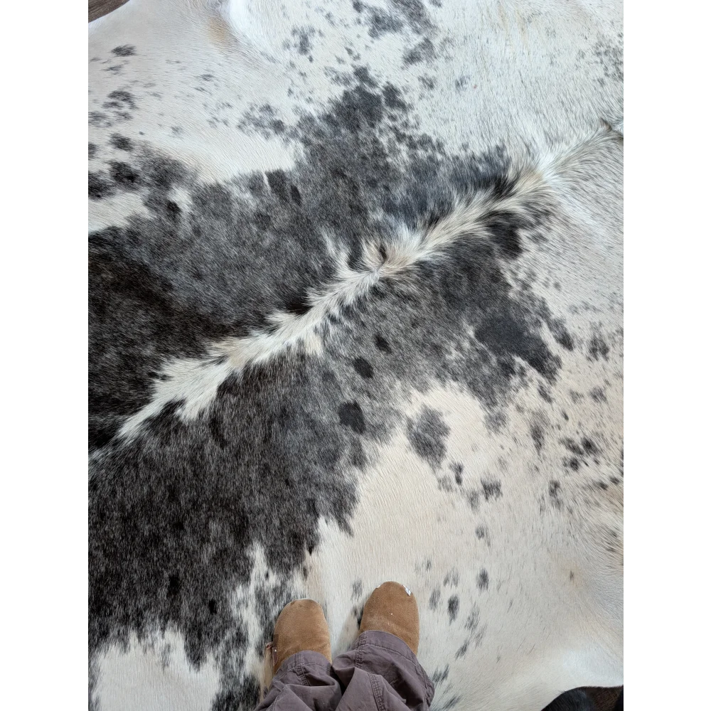 A beautiful large cowhide rug with a plush black and white spotted pattern adding rustic charm to any room