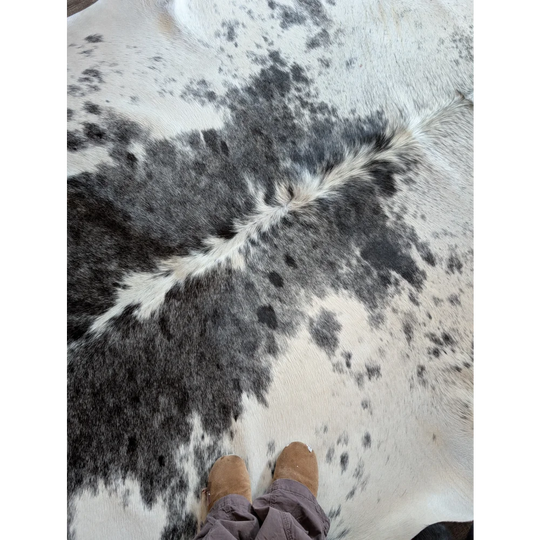 A beautiful large cowhide rug with a plush black and white spotted pattern adding rustic charm to any room