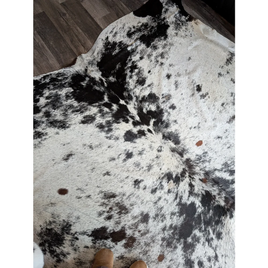 Large black and white spotted cowhide rug with natural fur texture adds rustic charm to beautiful rugs collection