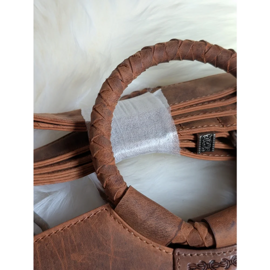 Brown leather sedona tassle bag with braided handle and decorative metal clasp in saddle brown