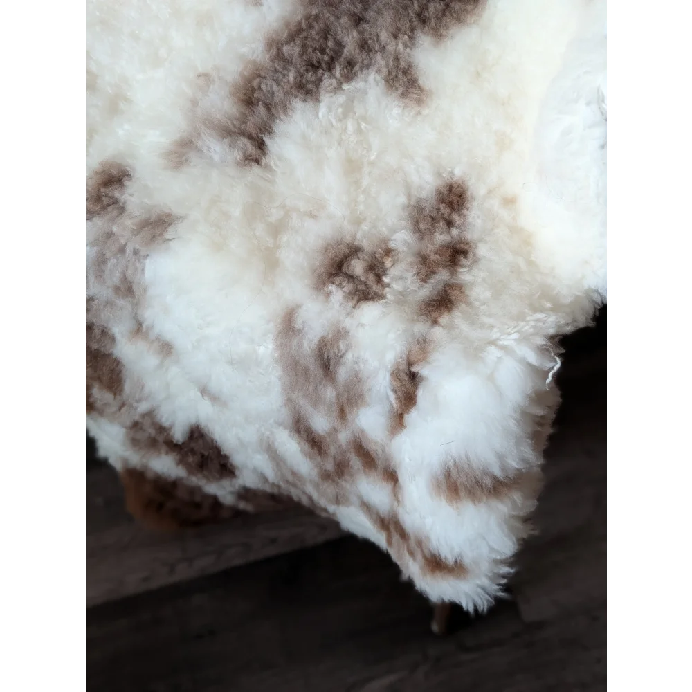 A plush cream and brown tibet highland spotted sheepskin rug with soft curly texture 47.5 by 26 inches