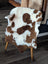 Brown and white tibet highland spotted sheepskin rug draped over wooden chair showing soft texture and natural pattern