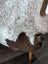A cozy cream and brown tibet highland spotted sheepskin throw draped over a wooden chair leg