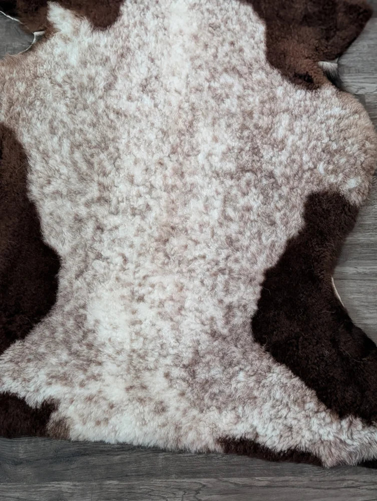 A plush tibet highland spotted sheepskin rug with a soft white and brown speckled pattern size 39x26 inches