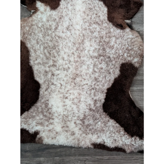 A plush tibet highland spotted sheepskin rug with a soft white and brown speckled pattern size 39x26 inches