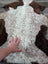 A plush 39 x 26 inch tibet highland spotted sheepskin rug with curly fur in natural white and brown colors