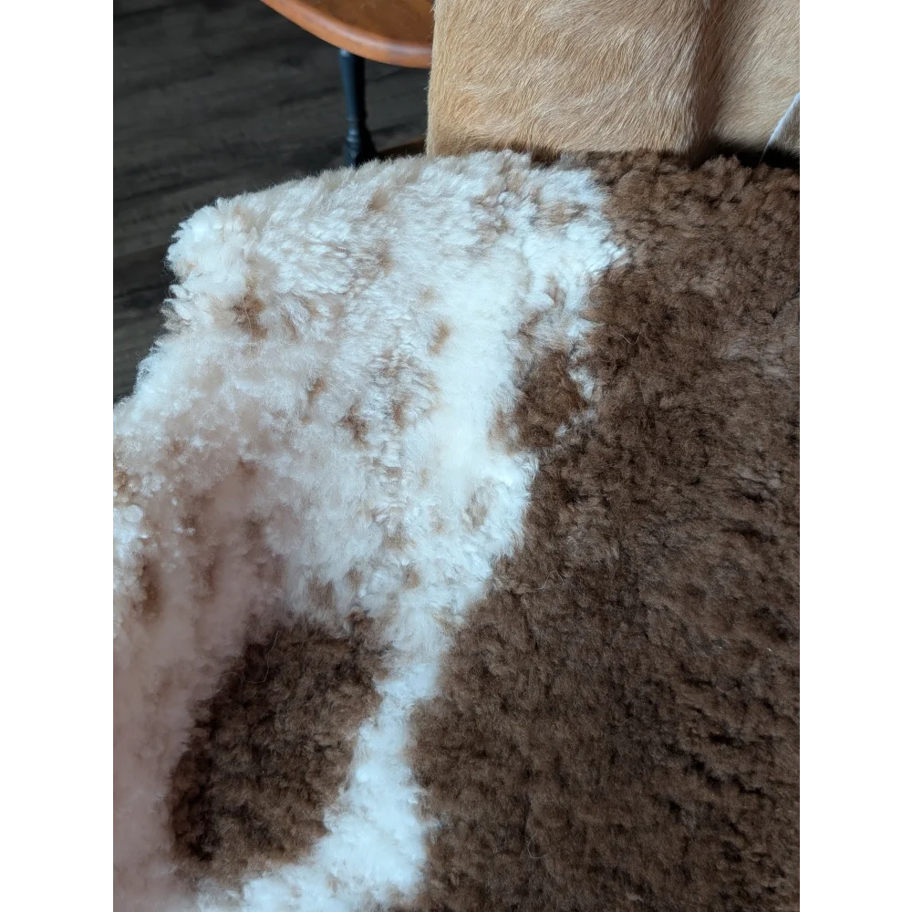 A plush 40 x 25 inch tibet highland spotted sheepskin rug with soft white and brown fur texture grade a quality