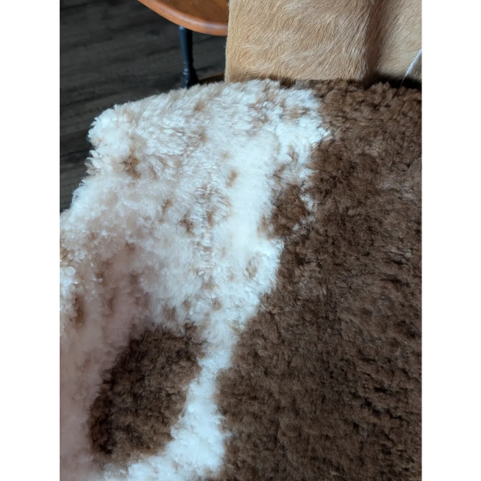A plush 40 x 25 inch tibet highland spotted sheepskin rug with soft white and brown fur texture grade a quality