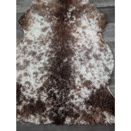 A plush tibet highland spotted sheepskin rug with cream and brown curls perfect for cozy home decor