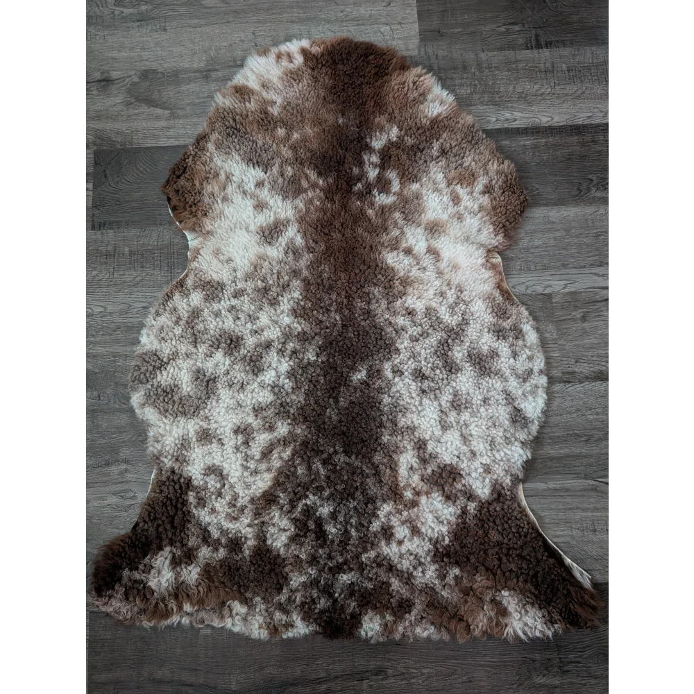 A plush tibet highland spotted sheepskin rug with soft brown and white fur measuring 40 by 26 inches