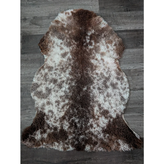 A plush tibet highland spotted sheepskin rug with soft brown and white fur measuring 40 by 26 inches