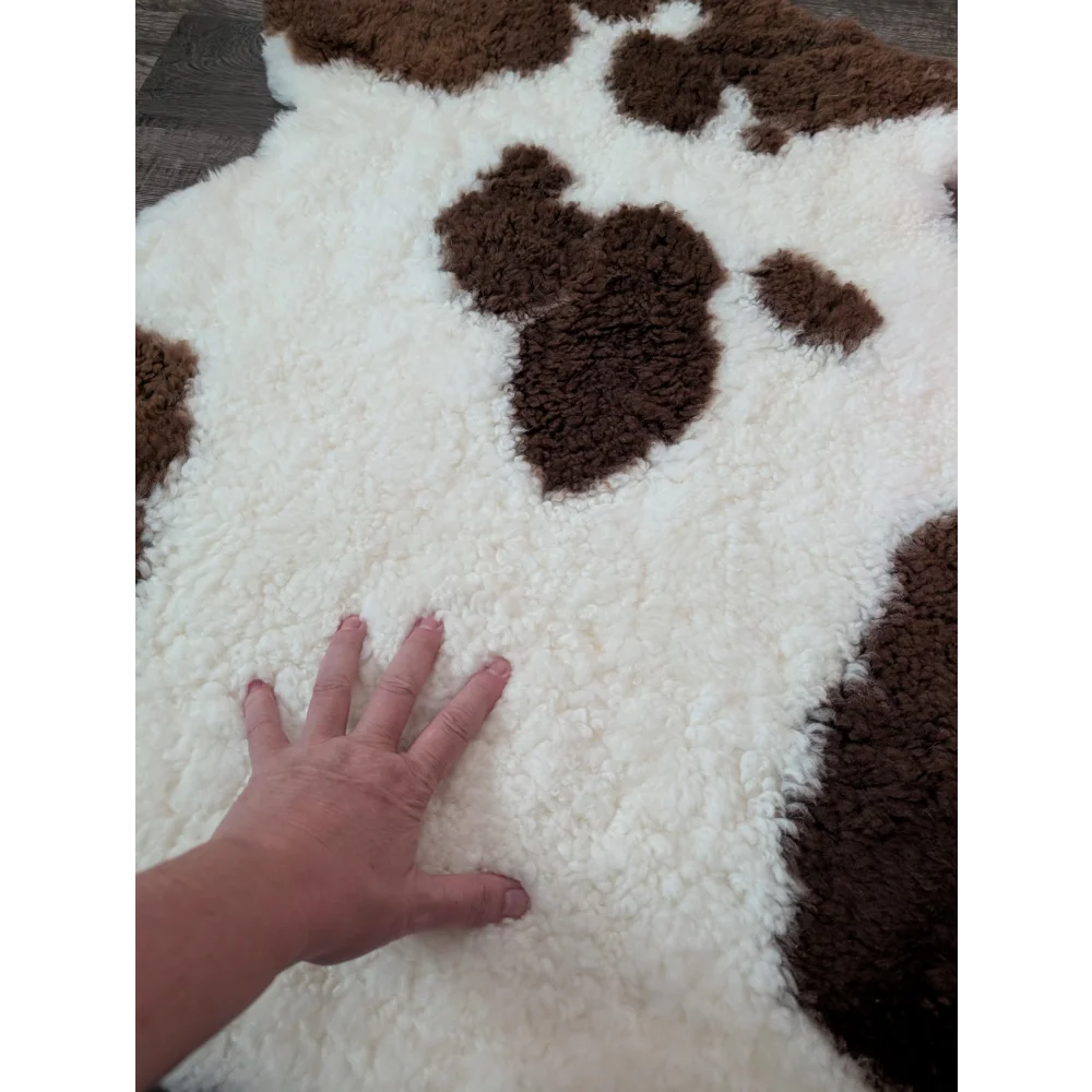 A plush white and brown highland spotted sheepskin rug with soft fluffy texture perfect for cozy decor