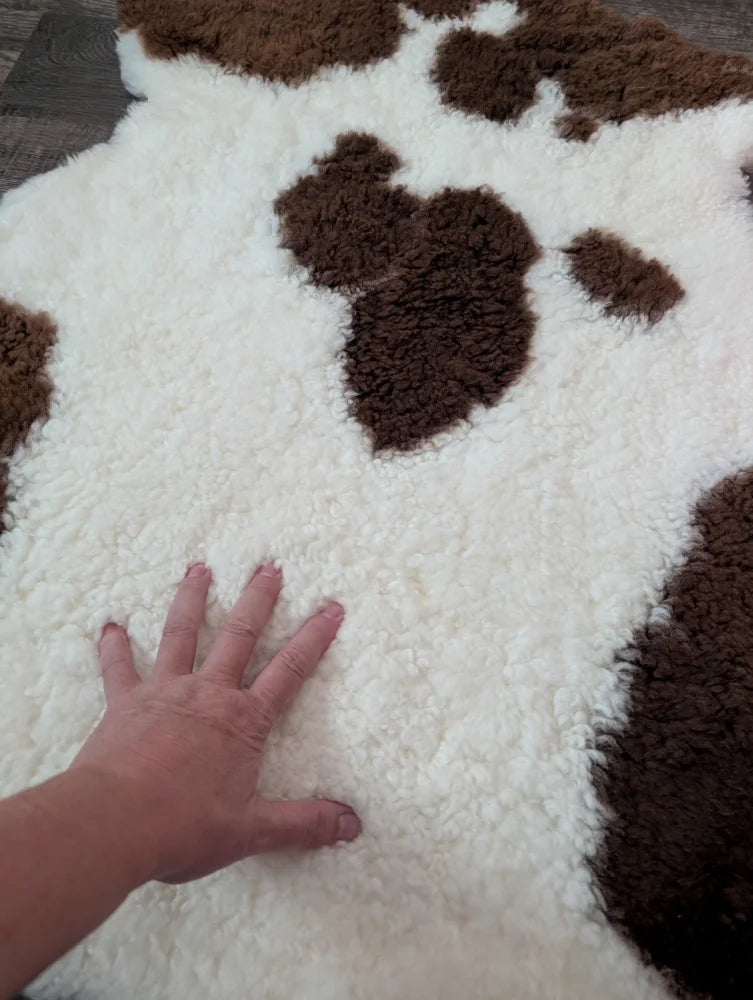 A plush white and brown highland spotted sheepskin rug with soft fluffy texture perfect for cozy decor