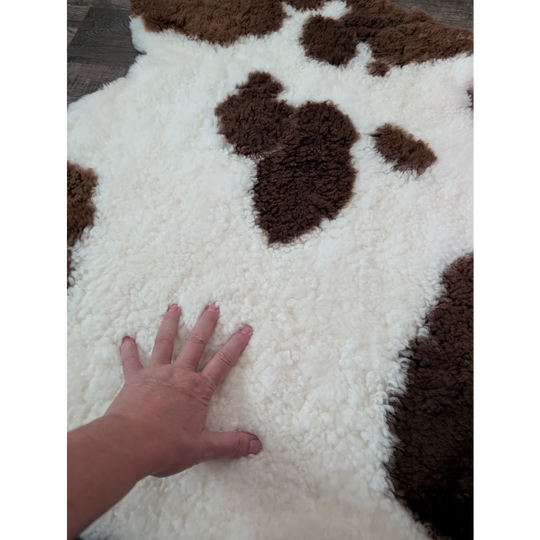 A plush white and brown highland spotted sheepskin rug with soft fluffy texture perfect for cozy decor