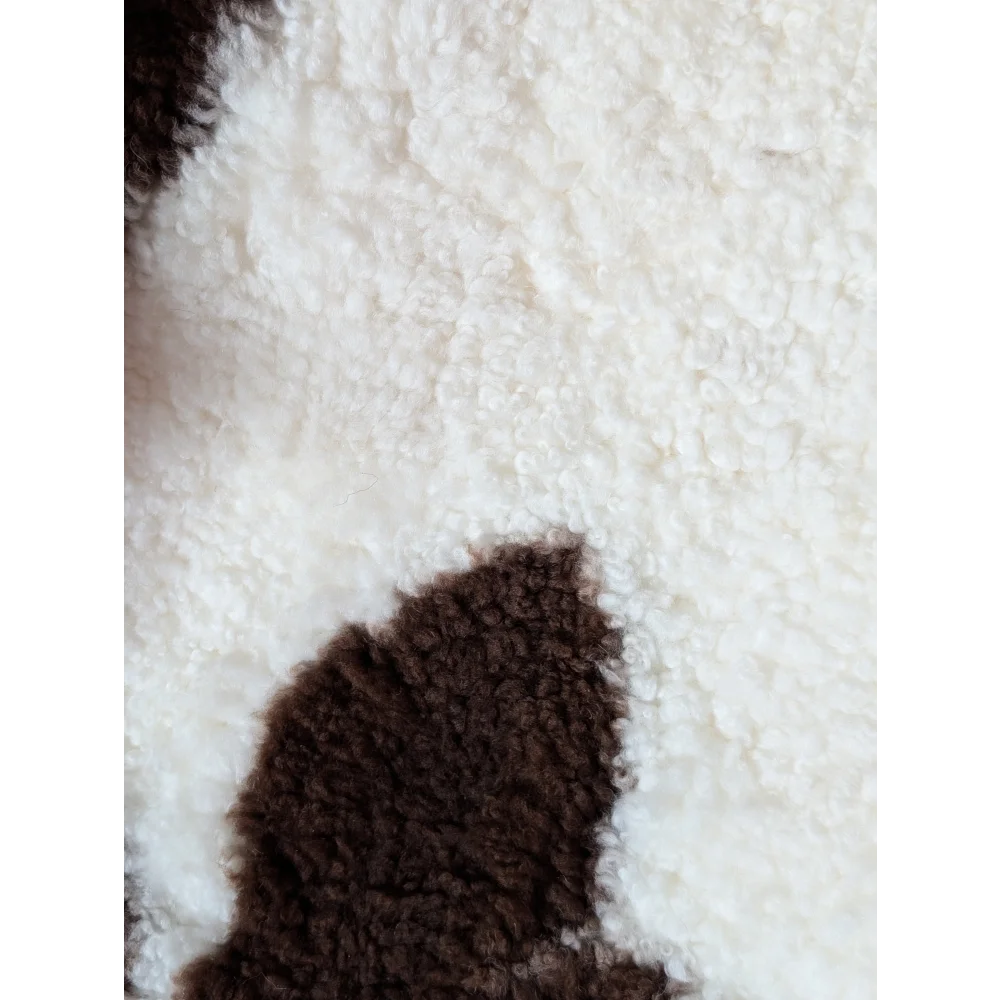 White and brown fluffy tibet highland spotted sheepskin with plush textured surface in size 41.5 by 25.5 inches