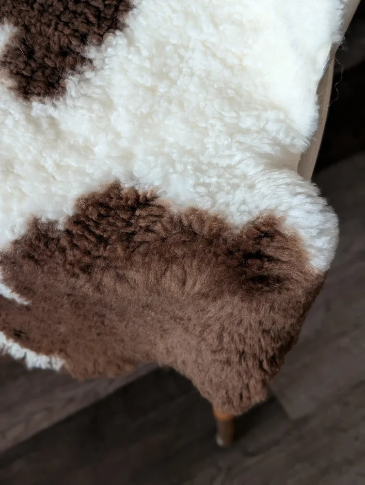 A plush tibet highland spotted sheepskin rug in white and brown spots perfect for cozy home decor
