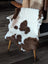 A plush white and brown highland spotted sheepskin throw draped over a wooden chair made from tibet highland spotted material