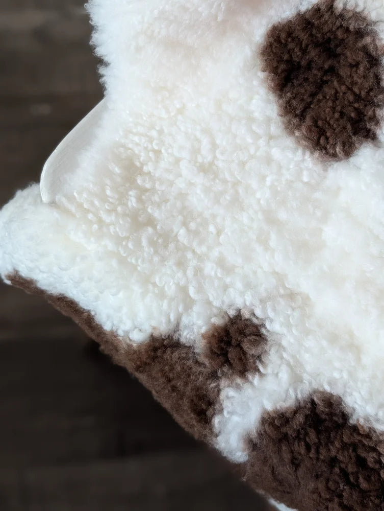 A plush 41.5 x 25.5 inch tibet highland spotted sheepskin blanket with soft curly white and brown highland spotted fur