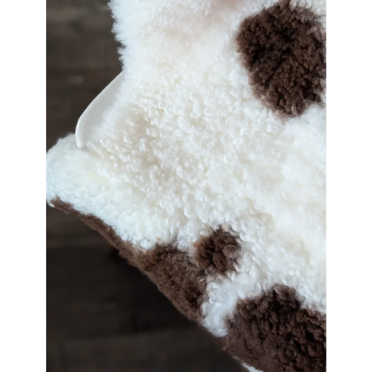 A plush 41.5 x 25.5 inch tibet highland spotted sheepskin blanket with soft curly white and brown highland spotted fur
