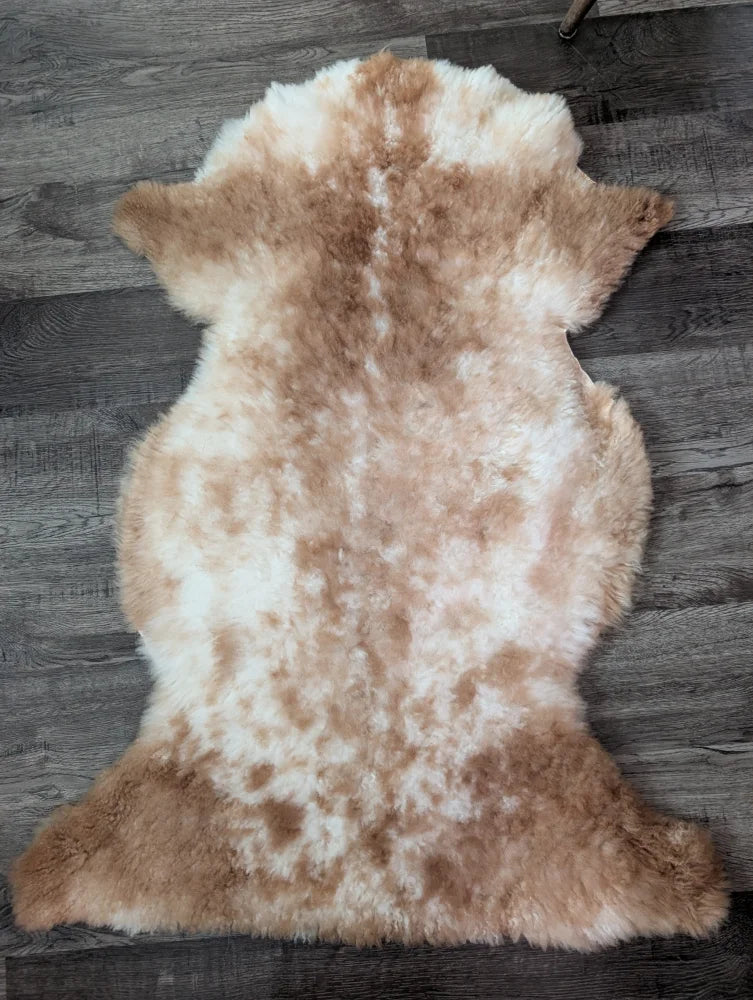 A soft fluffy tibet highland spotted sheepskin rug in creamy white and light brown perfect for cozy decor
