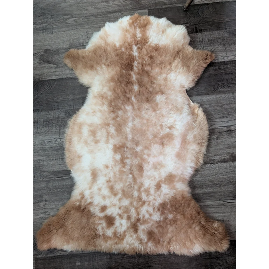 A soft fluffy tibet highland spotted sheepskin rug in creamy white and light brown perfect for cozy decor