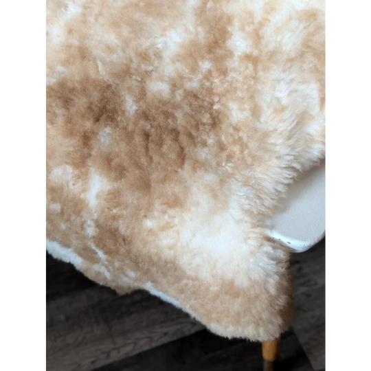 A plush cream and beige tibet highland spotted sheepskin throw with soft fluffy texture measuring 41.5 x 24.5 inches