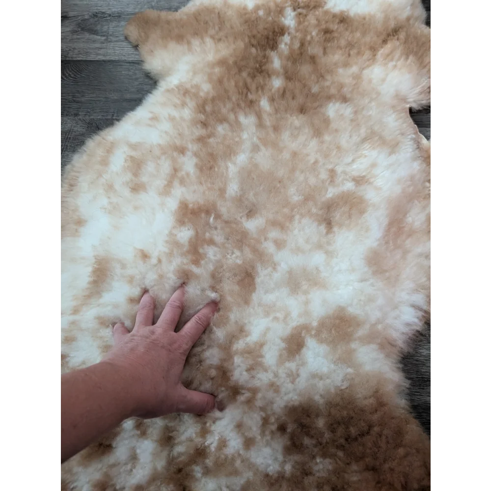 A soft fluffy grade a tibet highland spotted sheepskin rug in cream and light brown perfect for cozy decor