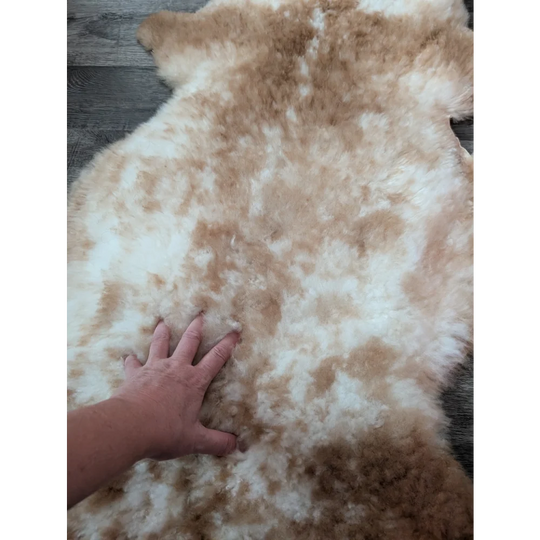 A soft fluffy grade a tibet highland spotted sheepskin rug in cream and light brown perfect for cozy decor