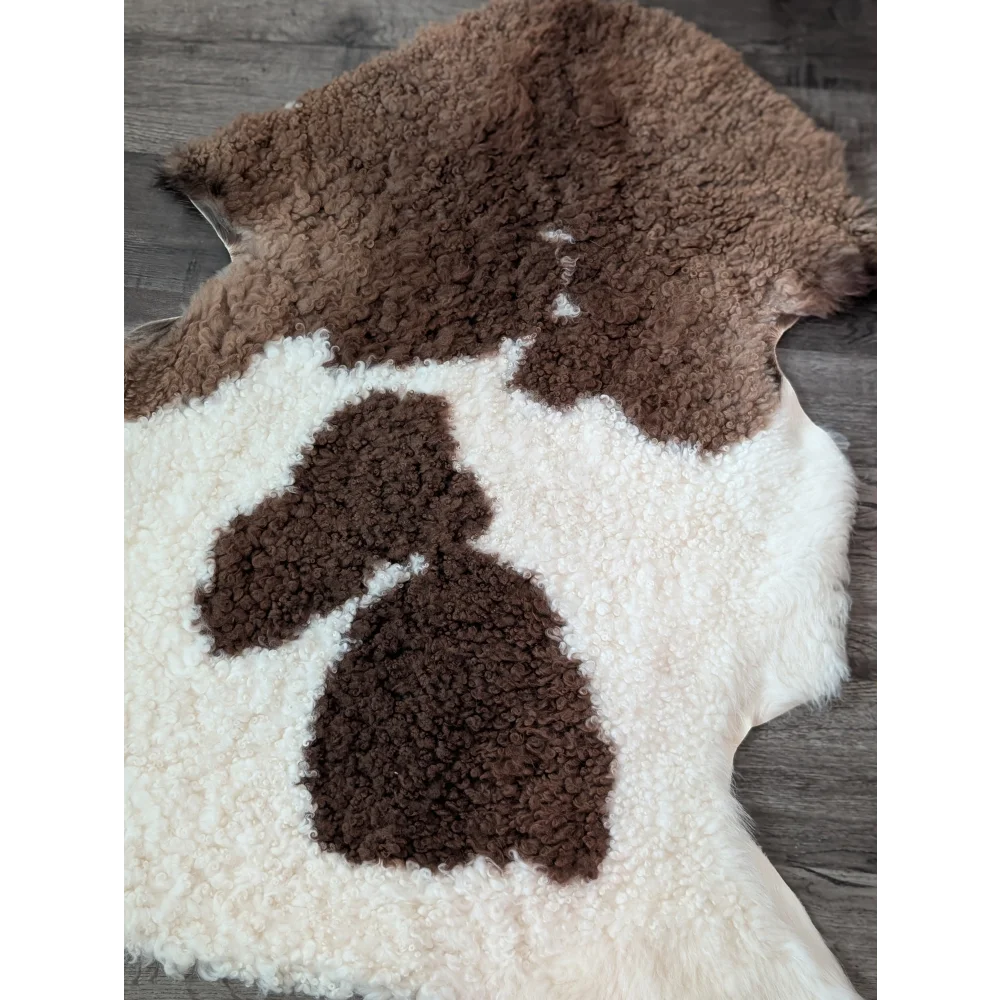 A plush cream and brown tibet highland spotted sheepskin rug with soft curly texture measuring 41 by 26.5 inches