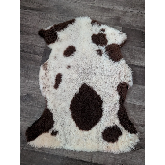 A plush white and brown highland spotted tibet highland spotted sheepskin rug with soft fluffy texture and grade a quality
