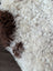 A plush white and brown tibet highland spotted sheepskin rug with a soft curly texture in size 42 by 27 inches
