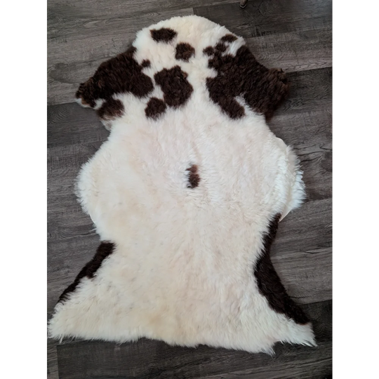 A plush cream and brown tibet highland spotted sheepskin rug with natural fluffy texture sized 43 x 27 inches