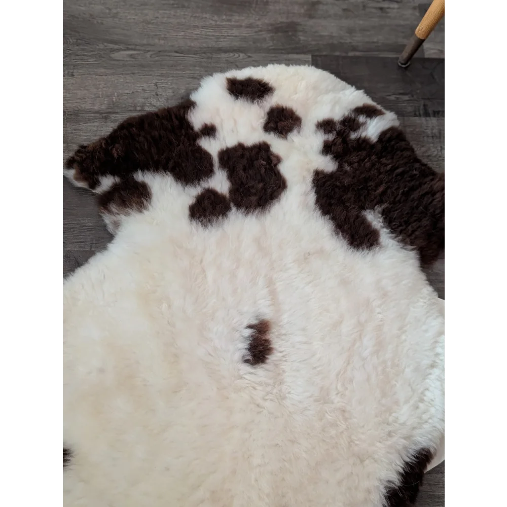 A cream and dark brown tibet highland spotted sheepskin rug measuring 43 by 27 inches made of plush grade a material