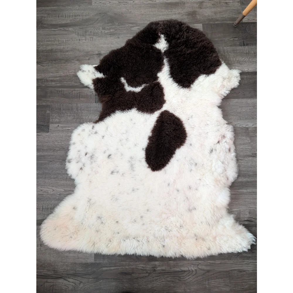 A plush irregular highland spotted sheepskin rug in natural white with bold dark brown patches from tibet highland