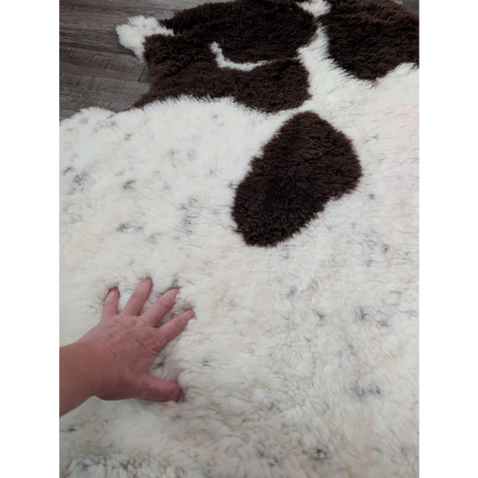 A plush white and brown highland spotted sheepskin rug with soft fluffy texture perfect for cozy decor