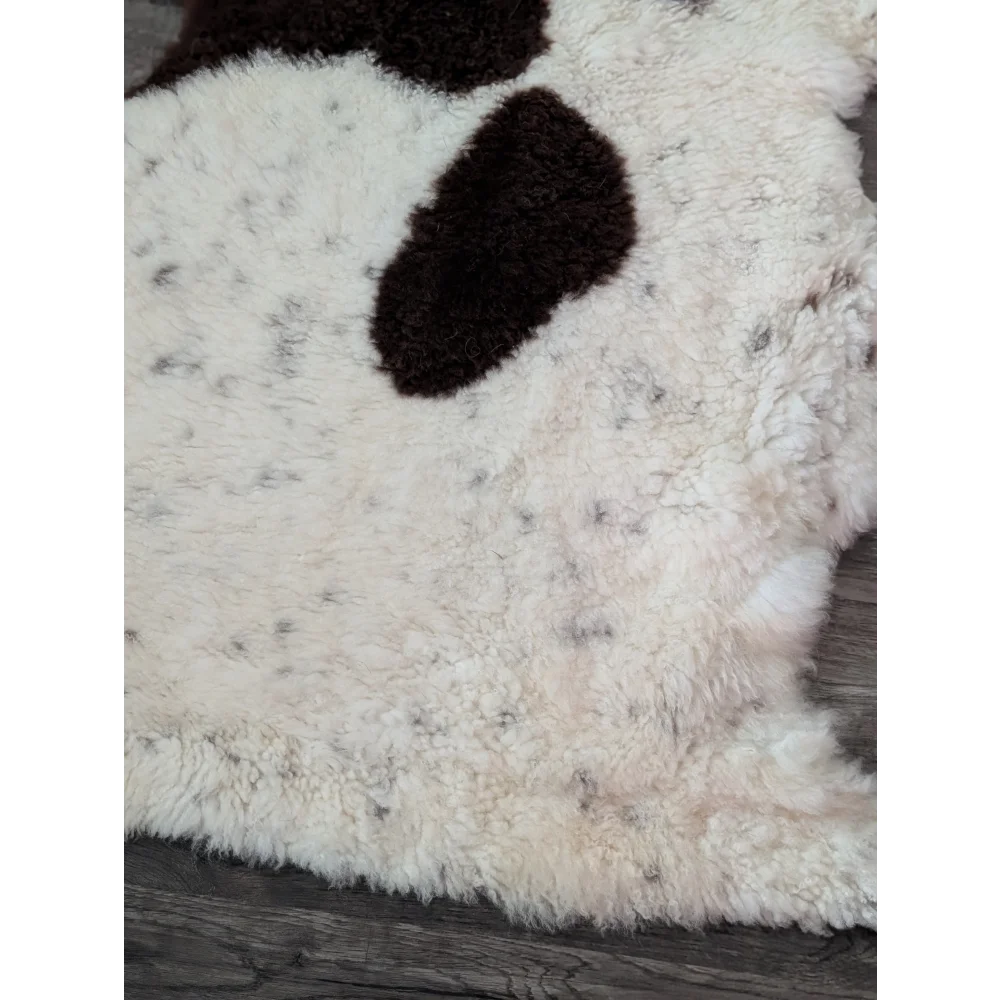 A grade a tibet highland spotted sheepskin rug with plush white and irregular dark brown patches, soft and fluffy texture