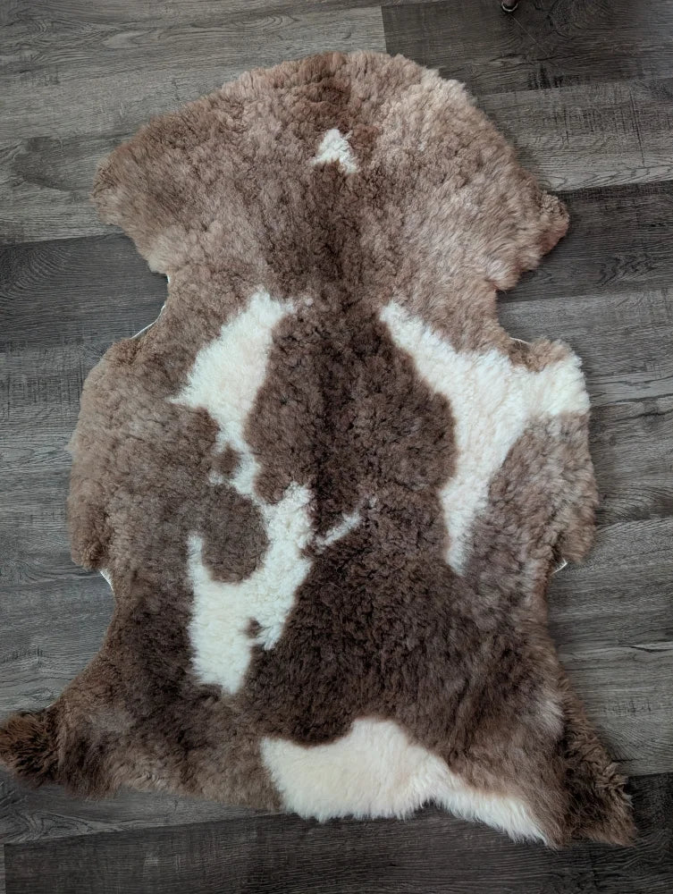A plush tibet highland spotted sheepskin rug in soft brown and white spotted pattern measuring 41.5 by 26 inches