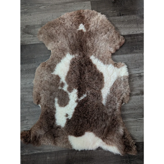 A plush tibet highland spotted sheepskin rug in soft brown and white spotted pattern measuring 41.5 by 26 inches